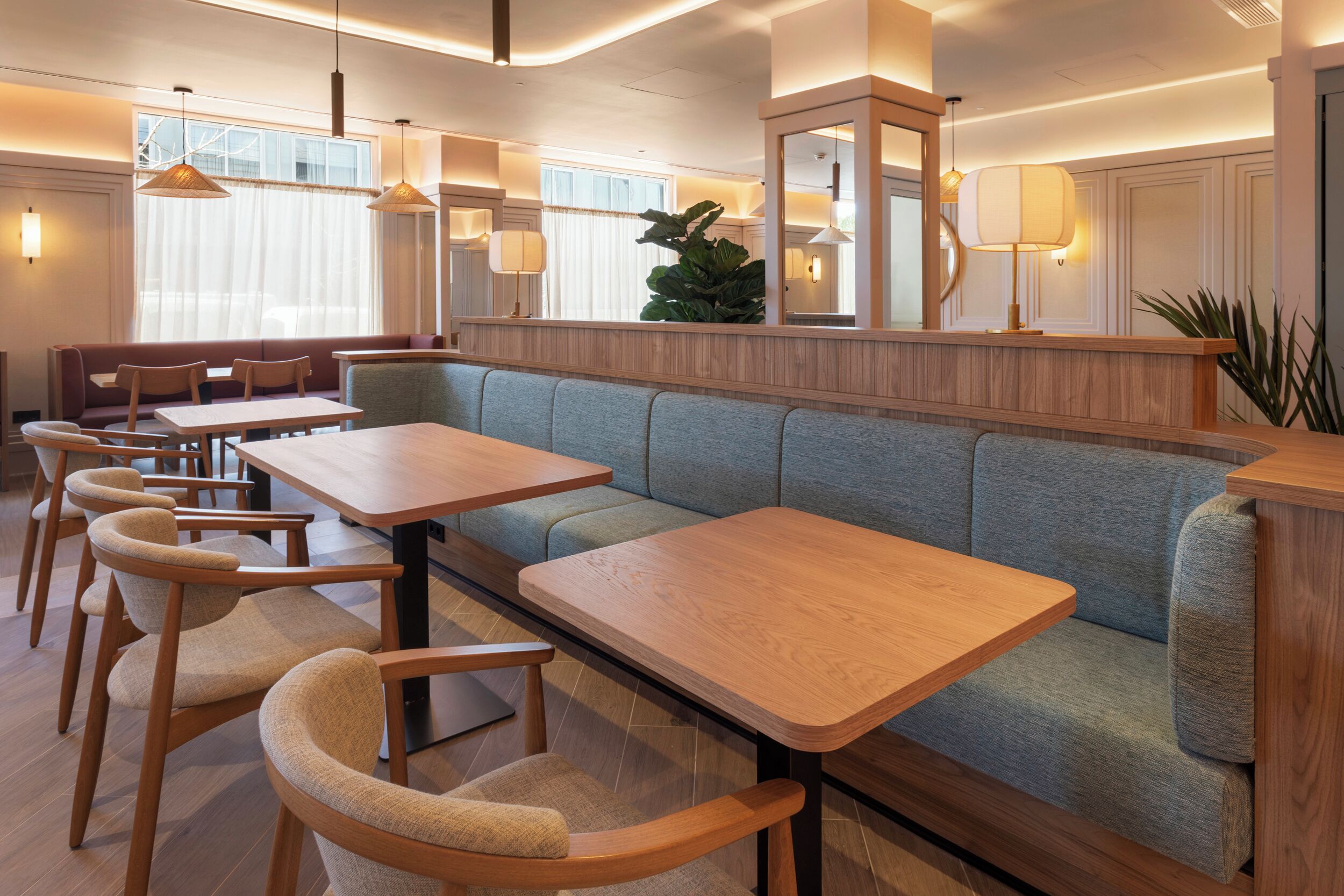 A modern dining area with wooden tables and cushioned seating.