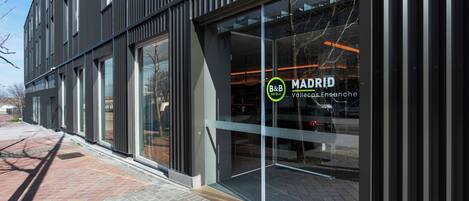 A modern building with large glass windows and a sign for B&B MADRID.