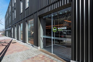 A modern building with large glass windows and a sign for B&B MADRID.