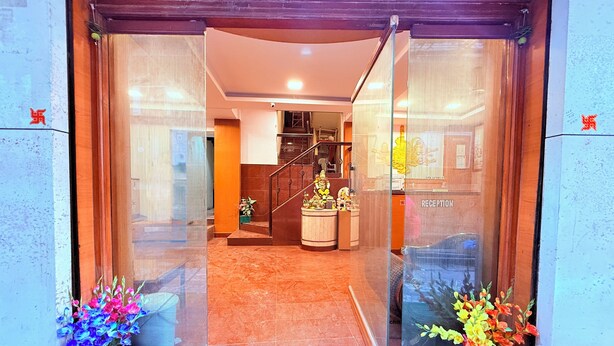 A hotel entrance with a reception desk, a staircase, and a statue of a deity. - ShivSagar Residency Zaveri Bazaar (Mumbai)