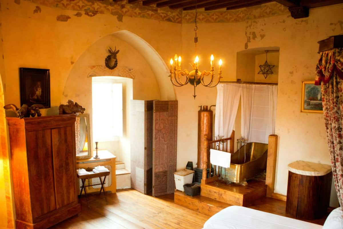 A rustic room with a wooden bed, a chandelier, a large mirror, and a window with curtains.