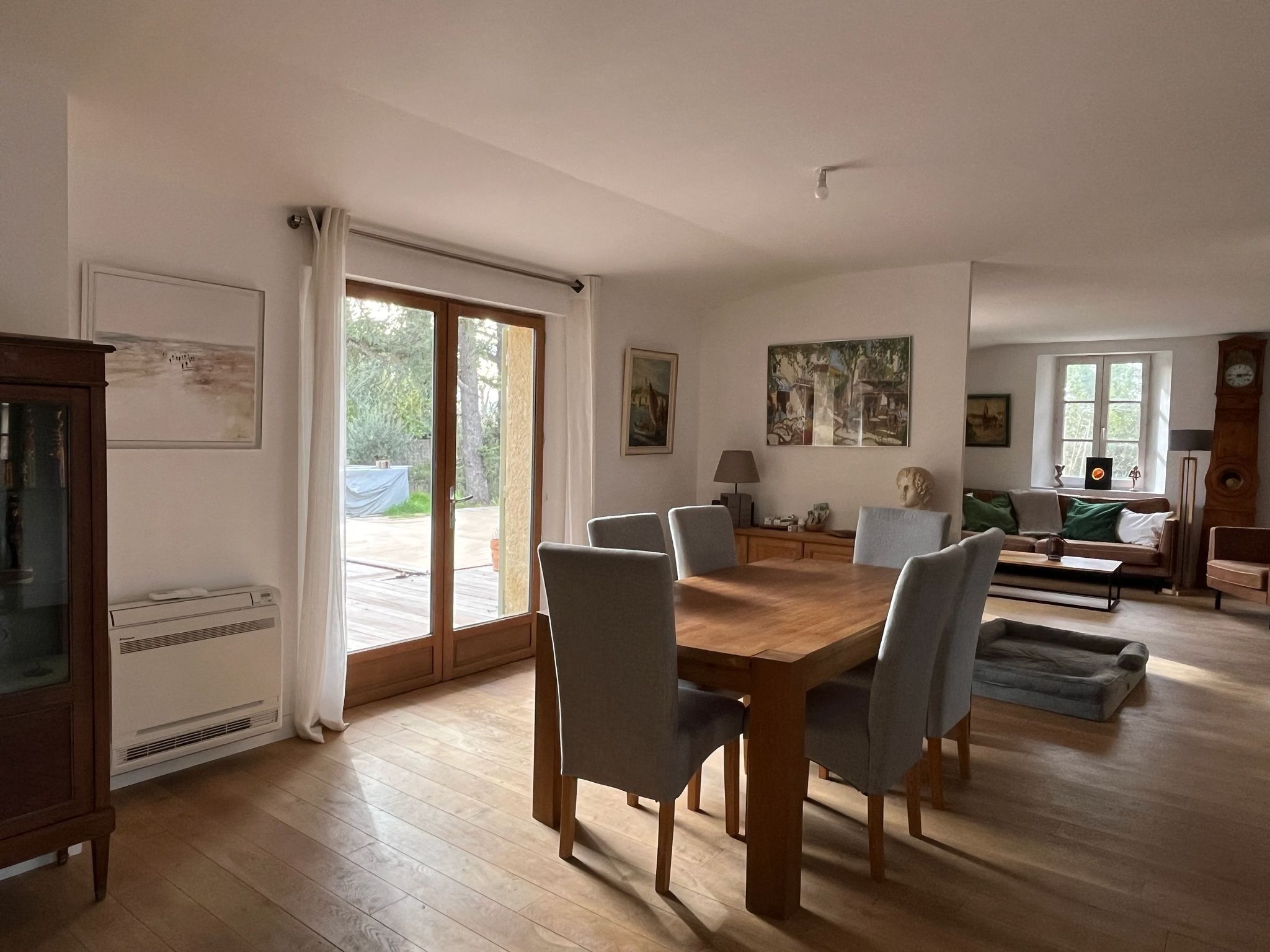 Un salon spacieux avec une table à manger en bois, des sièges confortables, une grande fenêtre et une cheminée accueillante.