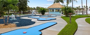 A pool area with a thatched-roof structure, a dolphin sculpture, and a water fountain. - 2 BR Deluxe Condo at Wyndham Cypress Palms (Kissimmee)