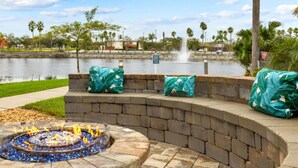 A fire pit with a circular stone design, surrounded by a brick wall and covered with green cushions. - 2 BR Deluxe Condo at Wyndham Cypress Palms (Kissimmee)