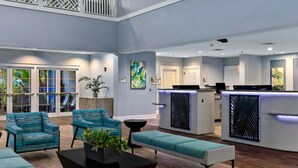 A modern reception area with a curved desk, seating with teal upholstery, and artwork on the walls. - 2 BR Deluxe Condo at Wyndham Cypress Palms (Kissimmee)