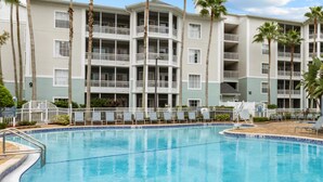 A hotel with a swimming pool, multiple balconies, and palm trees. - 2 BR Deluxe Condo at Wyndham Cypress Palms (Kissimmee)