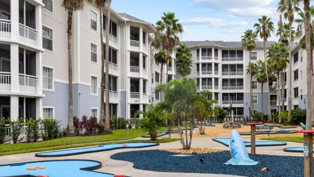 A multi-story hotel with balconies, palm trees, and a central water feature. - 2 BR Deluxe Condo at Wyndham Cypress Palms (Kissimmee)
