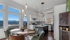 Una cocina moderna con armarios blancos, una isla central y una zona de comedor con una mesa redonda y sillas.