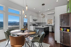 A modern kitchen with white cabinets, a central island, and a dining area with a round table and chairs. - Luxury in Sunshine Canyon - minutes from Boulder (Boulder)