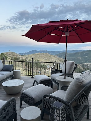 A deck with outdoor furniture, including sofas and chairs, and a red umbrella.