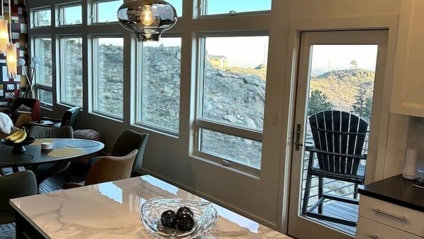 Una cocina moderna con encimera de mármol, luces colgantes y ventanas amplias que ofrecen vistas al exterior.