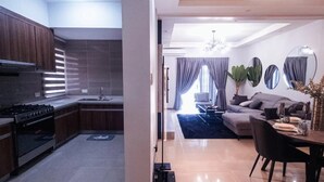 A modern kitchen with dark wooden cabinets and a stainless steel stove. - Valyron Homes (Accra)