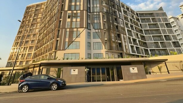 A multi-story building with a modern architectural design, featuring a prominent corner structure and a flat roof. - Valyron Homes (Accra)