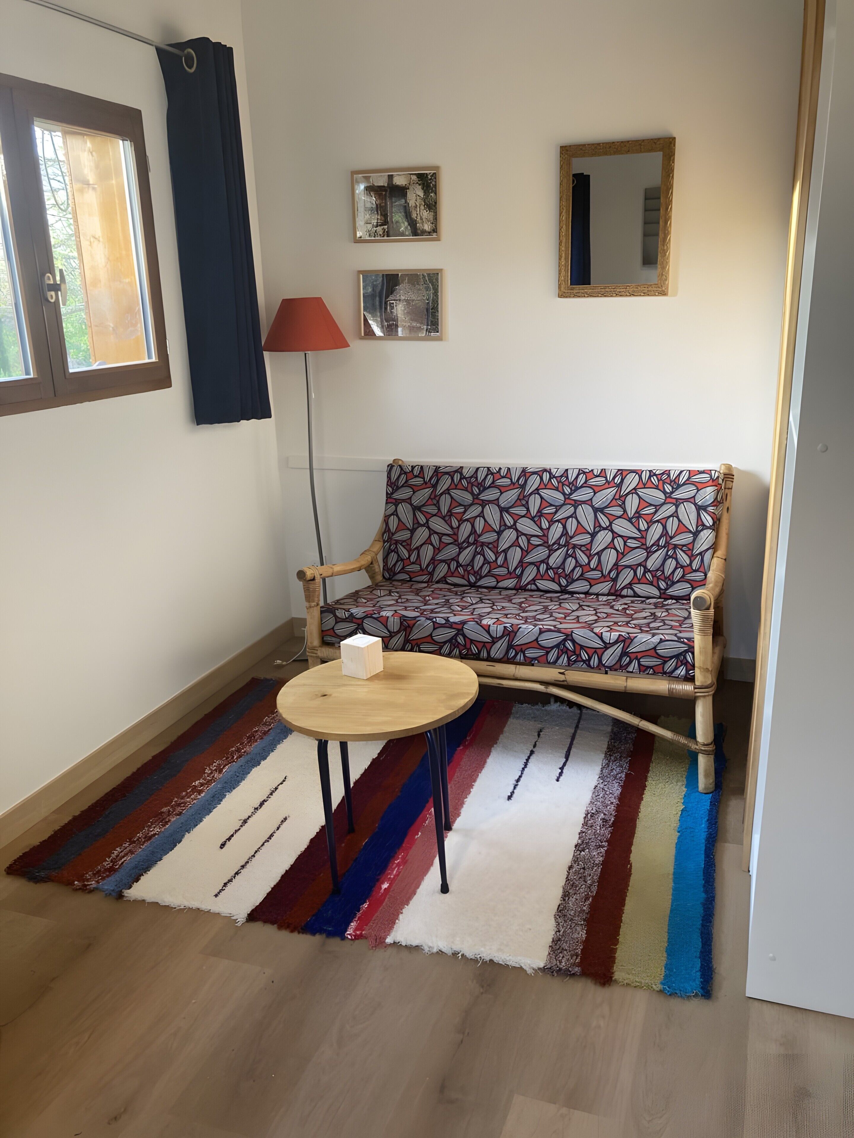 A room with a sofa, a round table, a lamp, and a window with curtains.