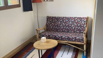 A room with a sofa, a round table, a lamp, and a window with curtains.