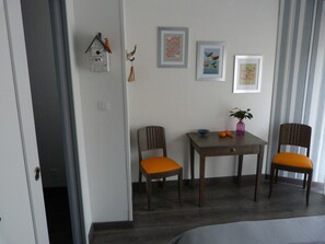 Ein Essbereich mit Tisch und Stühlen, einem an der Wand befestigten Vogelhaus und gerahmten Kunstwerken.