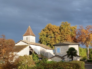 Eine Steinkirche mit einem Glockenturm und einem kleineren Gebäude mit Ziegeldach.