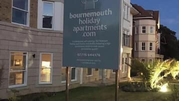 Une enseigne indiquant « Bournemouth holiday apartments.com », avec un immeuble moderne en arrière-plan.