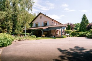 Une maison à deux étages dotée d’un porche abrité, entourée d’une végétation luxuriante et sous un ciel dégagé.