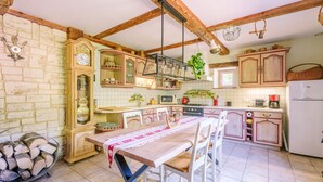 Een keuken met houten kastjes, een eettafel en een klok.