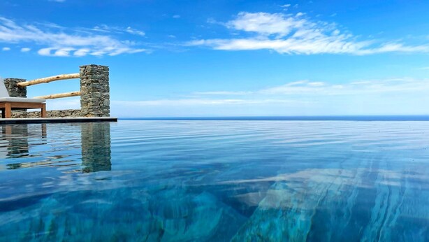 A infinity pool with a stone structure and a wooden bench. - Villa Thermaia | Wonderful Sea Views | Private Infinity Pool | Sifnos (Sifnos)