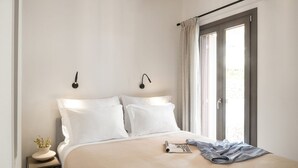 A neatly made bed with white linens, a bedside table with a lamp, and a window with curtains. - Villa Gaione, Divine Sea Views, Private Infinity Pool, Furnished Terrace, Sifnos (Sifnos)