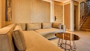 Ein modernes Wohnzimmer mit einem beigefarbenen Ecksofa, einem runden Couchtisch und einer Treppe, die zu einer weiteren Ebene führt.