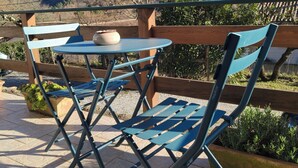 Une terrasse avec une table et des chaises, une vue sur un paysage montagneux et une clôture en bois.