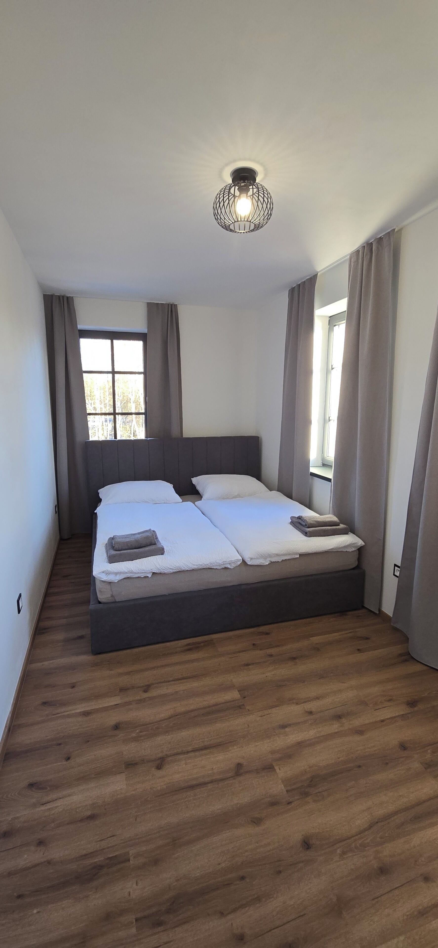 A bedroom with a bed, a window, and a ceiling light fixture.