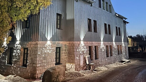 Un grand bâtiment d’un seul étage, doté d’un toit à pignon et de nombreuses fenêtres.