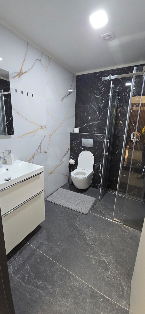 A modern bathroom with a toilet, sink, and shower area.