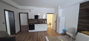 Una cocina compacta con armarios blancos, horno integrado y refrigerador.