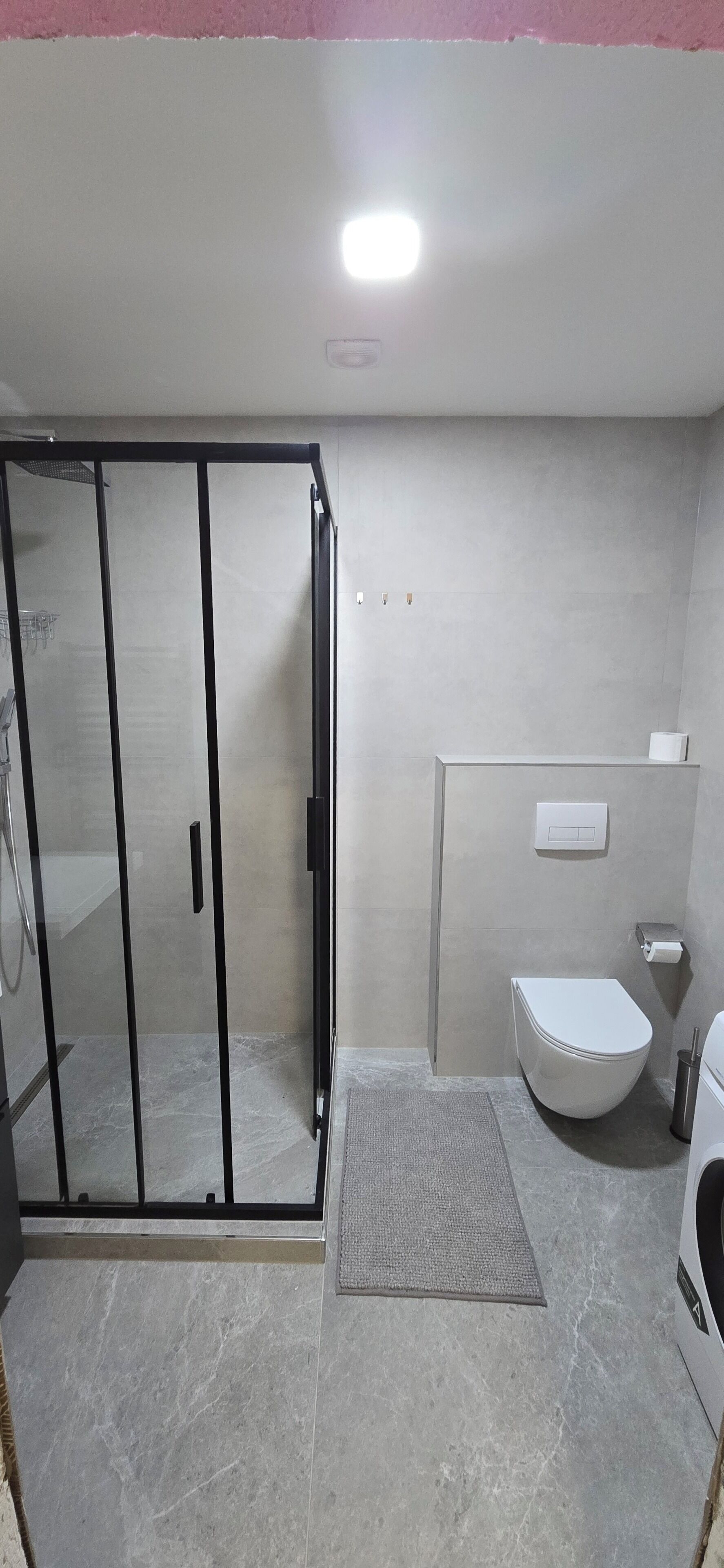 A modern bathroom with a glass shower enclosure, a toilet, and a bidet.