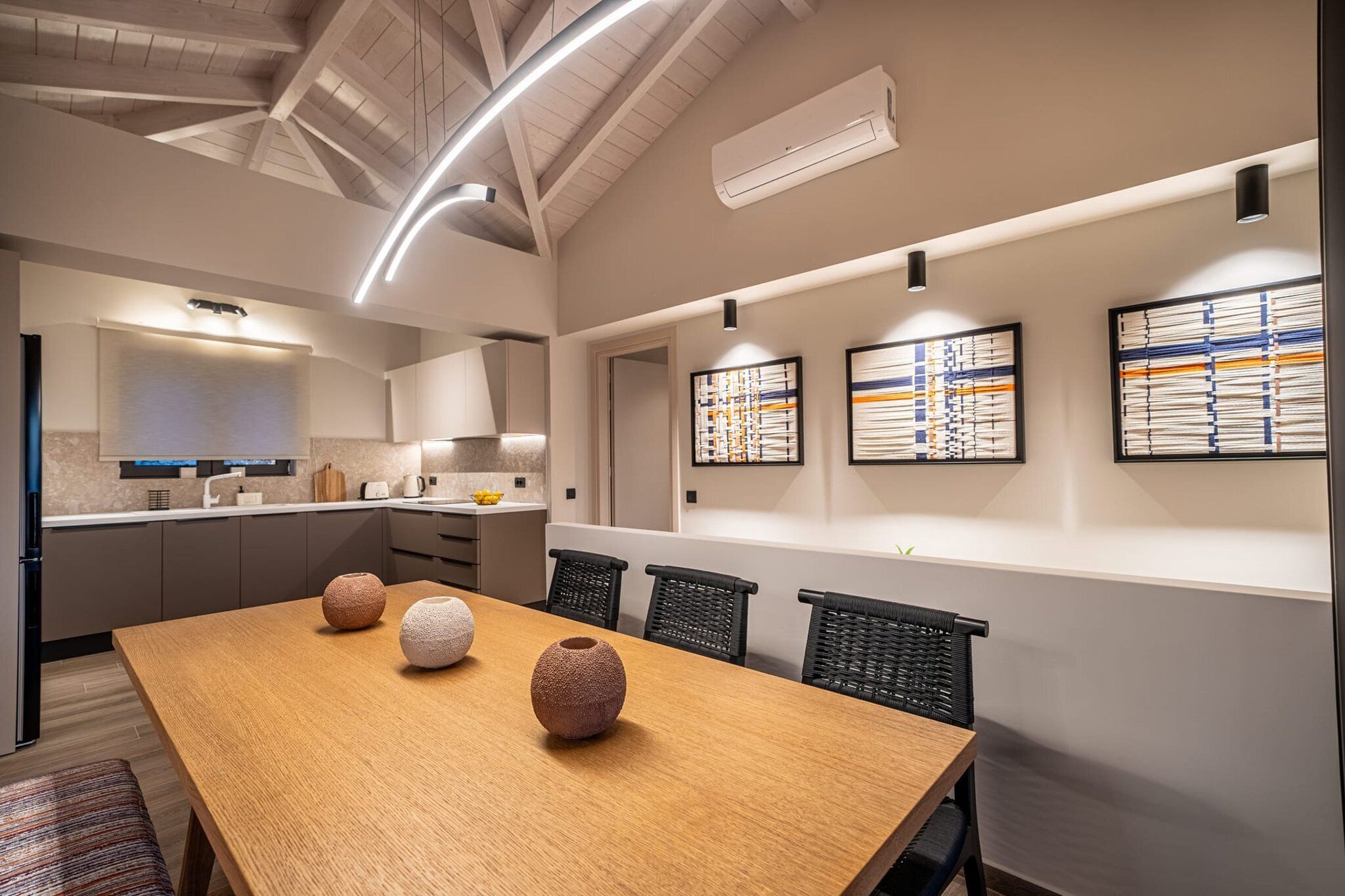 Une cuisine moderne avec une table et des chaises en bois, un four encastré et un luminaire suspendu.