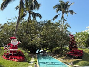 A pool area with a decorative Santa figure, palm trees, and a flower arrangement. - PENINSULA NUEVO VALLARTA BEAUTIFUL APARTMENT (Las Jarretaderas)