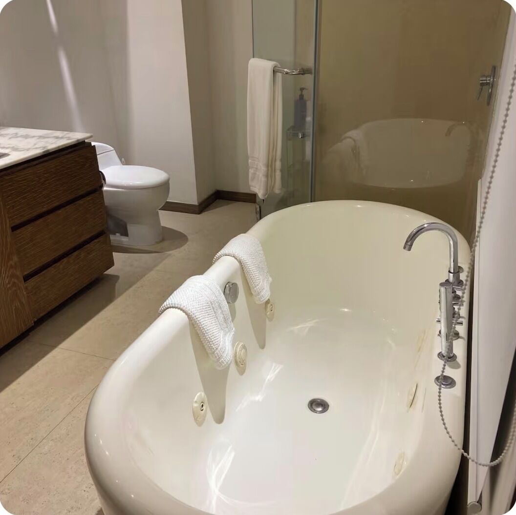 Une salle de bain moderne avec une baignoire sur pieds, des toilettes et un meuble-lavabo avec un miroir.