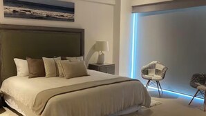 A modern bedroom with a large bed, a nightstand, a lamp, and two chairs. - PENINSULA NUEVO VALLARTA BEAUTIFUL CONDOMINIUM (Las Jarretaderas)