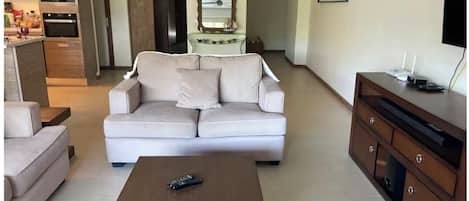 A living room with a sofa, a coffee table, and a TV stand.