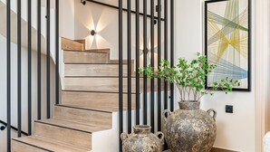 A staircase with wooden steps and black metal railings, accompanied by two rustic vases and a framed abstract painting. - Villa Philaea, Divine Sea Views, Private Pool, Furnished Terrace, Kefalonia (Kefalonia)