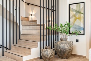 A staircase with wooden steps and black metal railings, accompanied by two rustic vases and a framed abstract painting. - Villa Philaea, Divine Sea Views, Private Pool, Furnished Terrace, Kefalonia (Kefalonia)