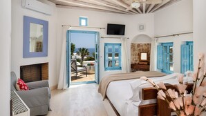 Um quarto com uma cama, uma cadeira, uma televisão e vista para o mar.