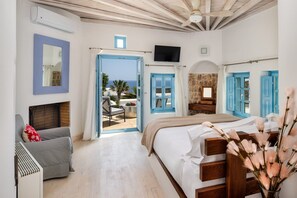 Ein Schlafzimmer mit Bett, Sessel, Fernseher und Meerblick.