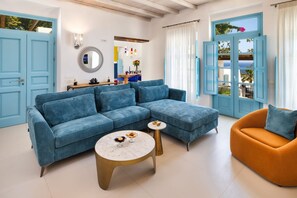 Ein Wohnzimmer mit einem blauen, modularen Sofa, einem runden Couchtisch und einem orangefarbenen Sessel.