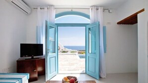 Una habitación con puerta abierta que da a un balcón con vistas al mar.