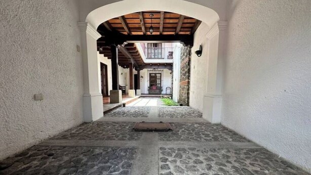 Un pasillo con suelo de piedra, techo abovedado y paredes blancas.