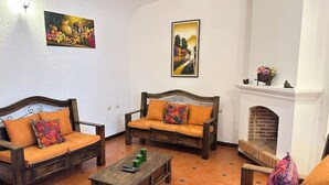 Una sala de estar acogedora con dos sofás de madera, una mesa de centro y una chimenea.