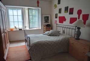 Ein Schlafzimmer mit Bett, Fenster, Kommode und Wanddekorationen.
