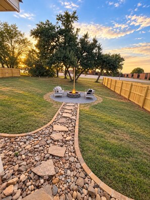 A backyard with a fire pit, two chairs, and a stone pathway. - The Loves’ Shack With Fire Pit, EV Charger, near I40, AR Nuclear 1 & Data Center (Clarksville)