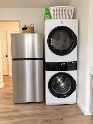 A compact kitchen with a stainless steel refrigerator and a white washing machine. - The Loves’ Shack With Fire Pit, EV Charger, near I40, AR Nuclear 1 & Data Center (Clarksville)
