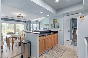 Una cocina moderna con una isla central, armarios de madera y una zona de comedor con mesa y sillas.